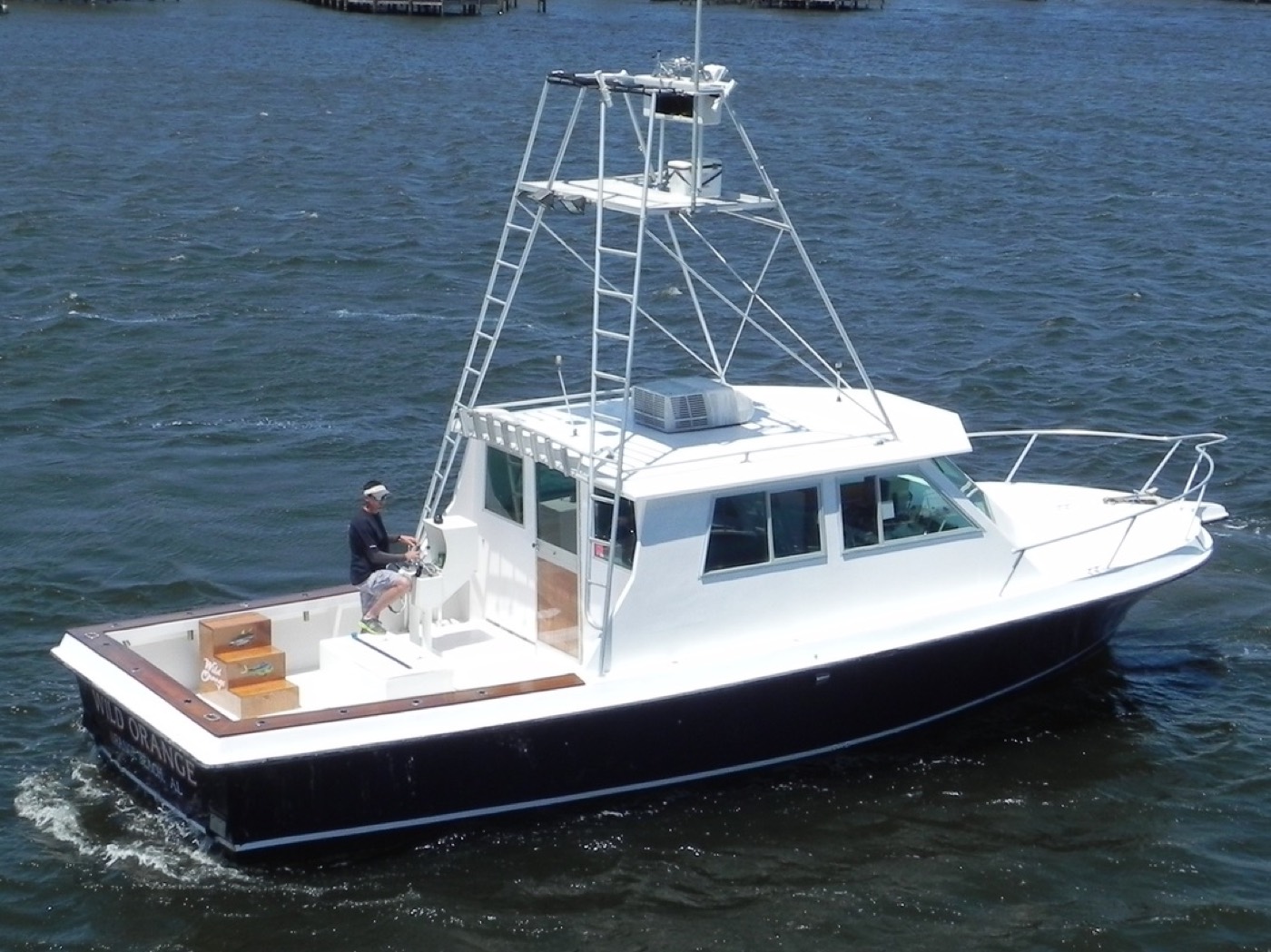 The Wild Orange underway off Orange Beach — 38-foot sportfisher with tuna tower, captain at the back-deck helm